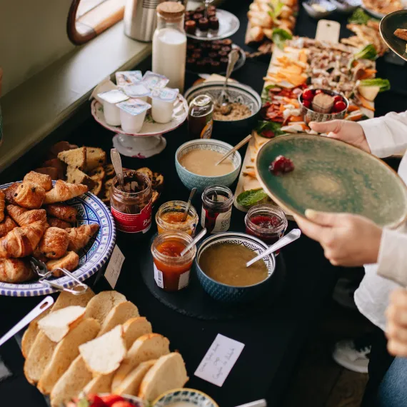 Buffet de brunch sucré-salé servi à bord d'une croisière sur la Garonne à Bordeaux, avec viennoiseries, fromages, charcuterie, tartines, fruits frais et boissons.