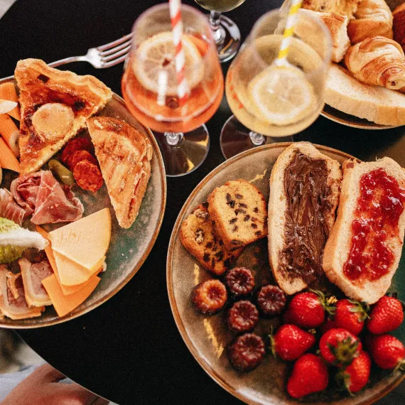 Assortiment de mets sucrés et salés servi lors d'un brunch-croisière à Bordeaux, avec viennoiseries, fromages, charcuterie, tartines, fruits frais et boissons.
