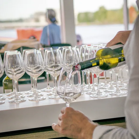 Service d'un verre de vin blanc lors d'une croisière dégustation sur la Garonne à Bordeaux.