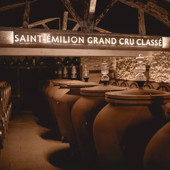 Chai viticole de Saint-Emilion Grand Cru Classé avec des cuves et des barriques en bois.