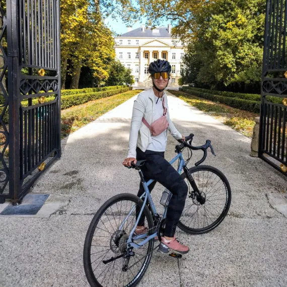 Cycliste à vélo devant un château entouré d’un parc arboré dans le vignoble bordelais.