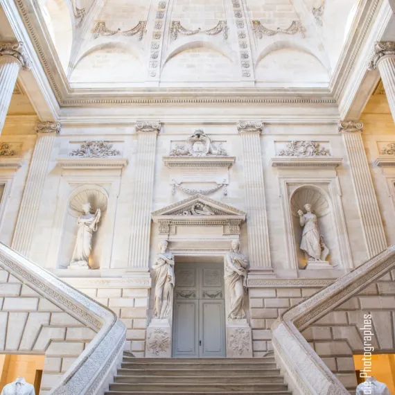 Vue de face de l'escalier d'honneur de l'Opéra National de Bordeaux, encadré de statues et d'une architecture néoclassique du XVIIIᵉ siècle.