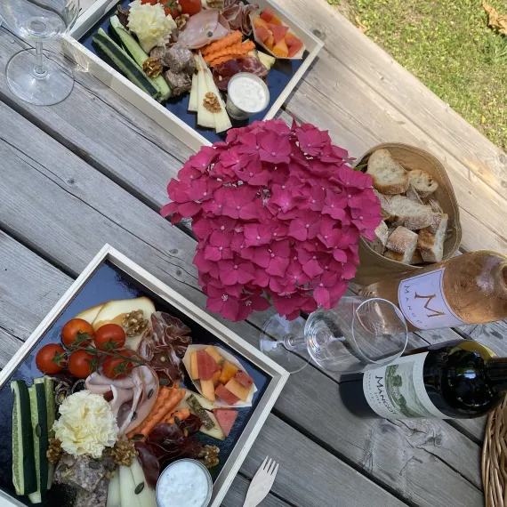 Pique-nique dans le parc du Château Mangot : planches de charcuterie, fromages, fruits, pain et bouteilles de vin rouge et rosé.