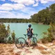 Cycliste à vélo devant un lac aux eaux turquoise au cœur des paysages naturels de Gironde.