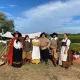 Groupe de personnes en costumes historiques dans les vignes, devant un campement d'époque.
