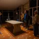 Un groupe de visiteurs découvre une cave viticole lors d'une visite guidée, entouré de casiers remplis de bouteilles de vin.