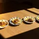 Planche de dégustation composée de morceaux de fromage, accompagnée de tartines garnies d'une préparation salée, présentées sur des assiettes rondes.