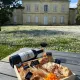Planche de charcuterie et fromages avec bouteille et verre de vin rouge Château Mangot, devant la façade du château, Saint-Émilion.