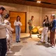 Groupe de visiteurs découvrant une cave viticole avec des barriques en bois pendant une visite guidée avant une dégustation de vin.