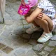 Une enfant observe les pavés de mémoire incrustés dans les rues pavées de Bordeaux.