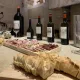 Dégustation de vins Château Mangot et Château La Brande dans le chai en pierre, accompagnée d'une planche de charcuterie et de pain.