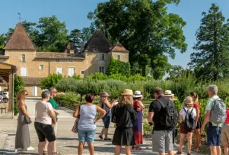 Besuchergruppe bei einer Führung vor einem Schloss mit spitzen Türmen und ockerfarbener Fassade, typisch für die Architektur von Bordeaux.